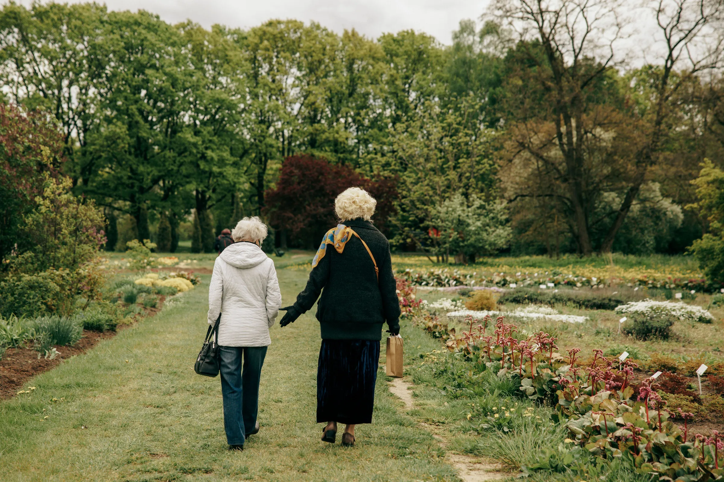 Zwei Frauen gehen nebeneinander einen Weg durch einen Park entlang